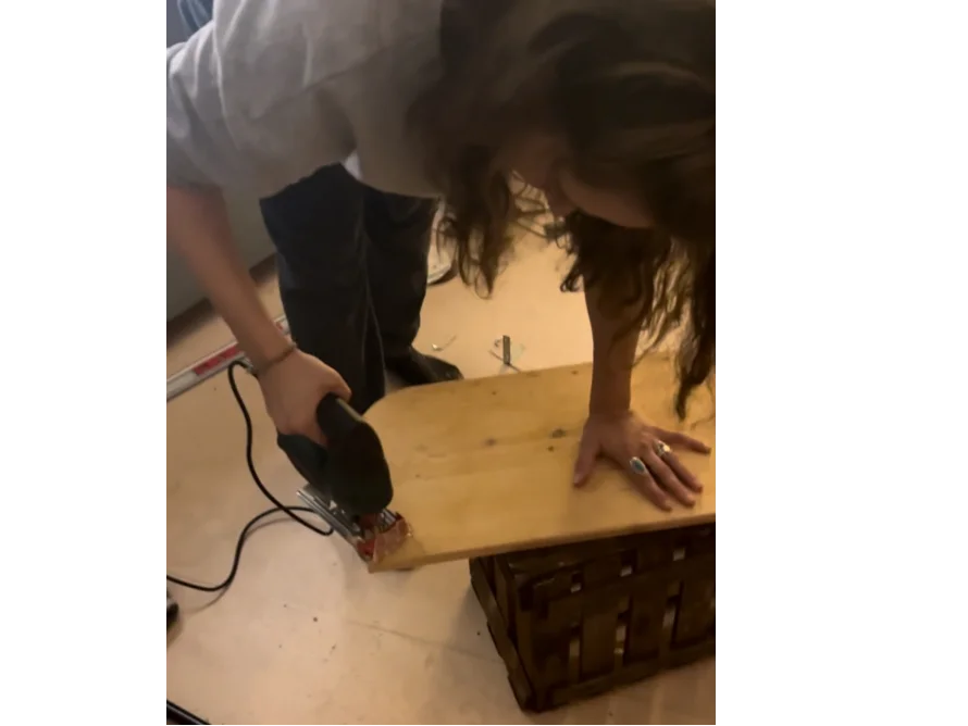 Person sägt ein Brett mit einer Stichsäge.