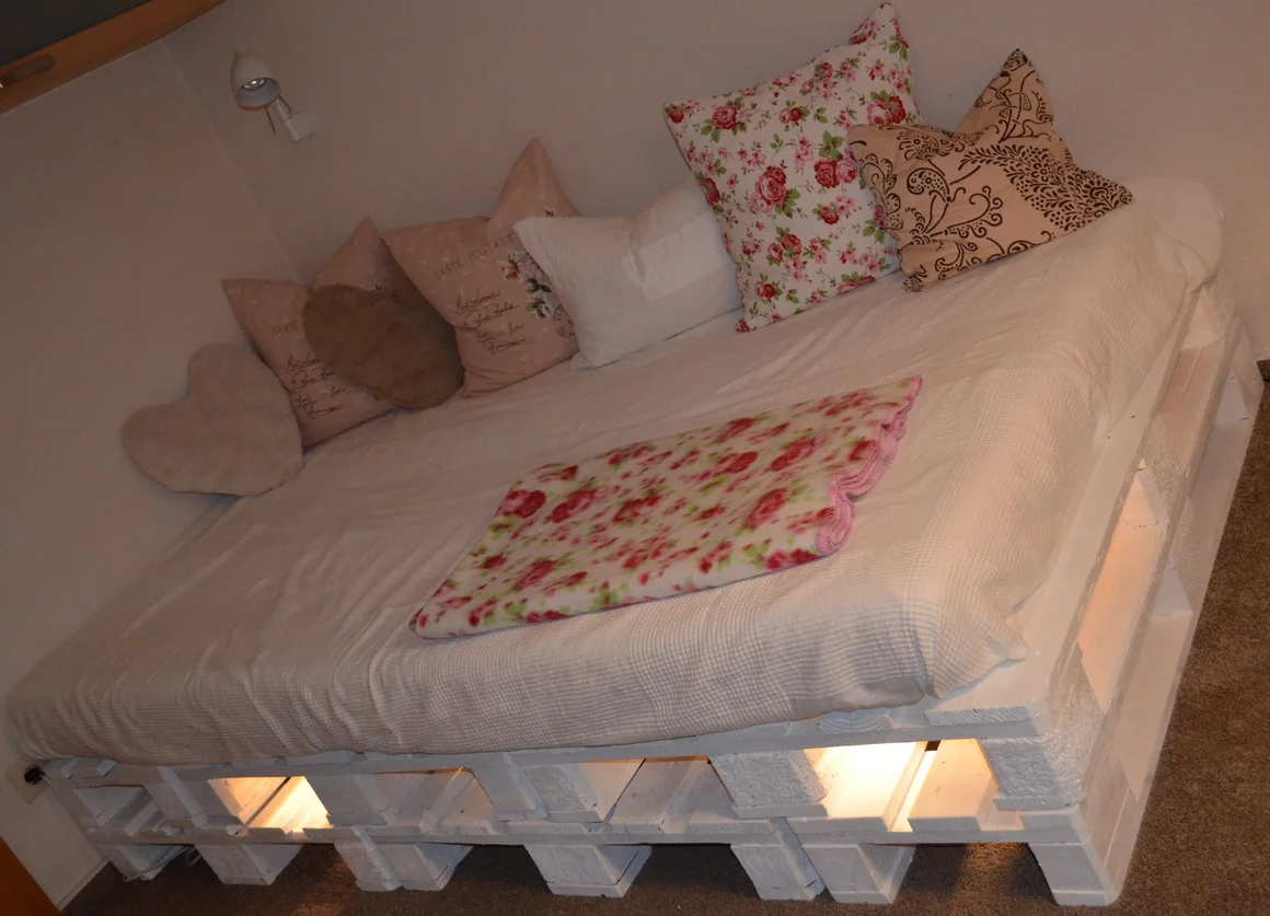 Bett aus weißen Paletten mit Beleuchtung