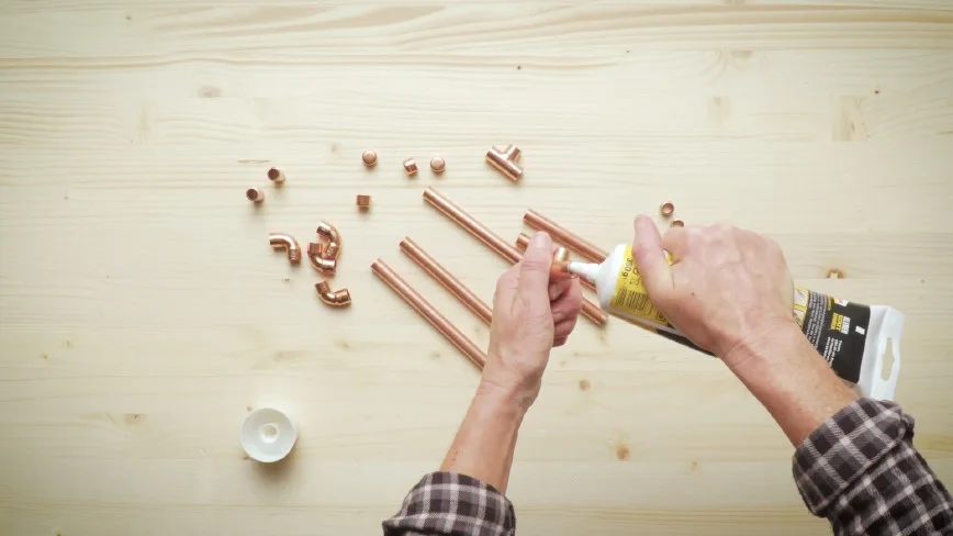 Person trägt Klebstoff auf Kupferrohr auf