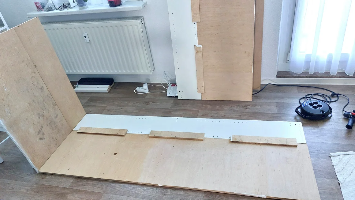 Zerlegte Möbelteile und Werkzeug liegen für den Aufbau auf dem Boden.