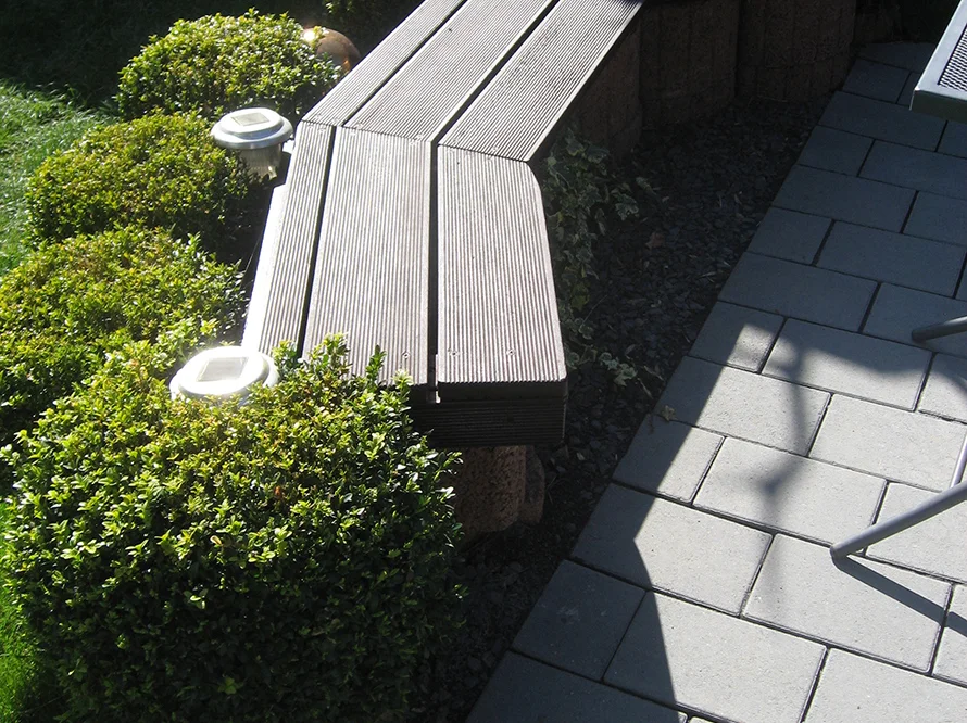 Holzbank an Pflasterweg mit Solarlampen