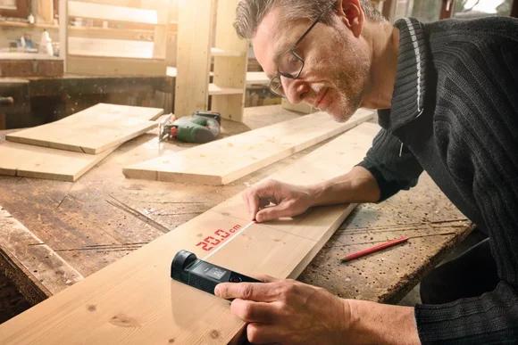 Person vermisst Holz mit Lasermessgerät