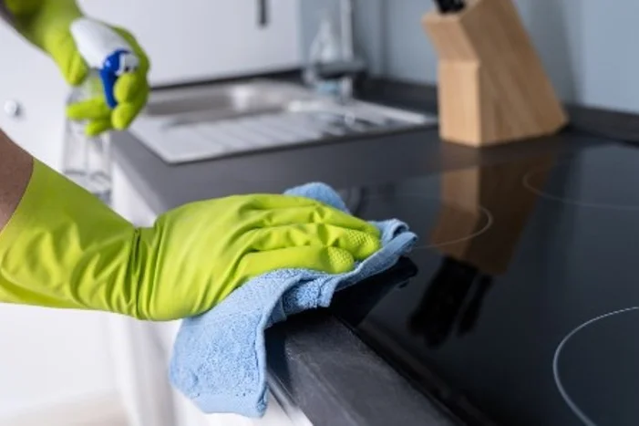 Hand reinigt Herd mit Lappen