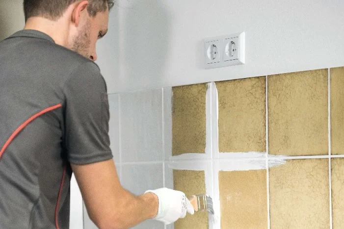 Person streicht Fliesenfugen mit Pinsel