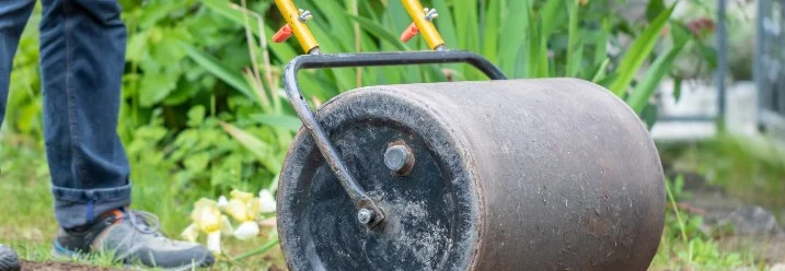 Person verwendet Gartenwalze auf Boden