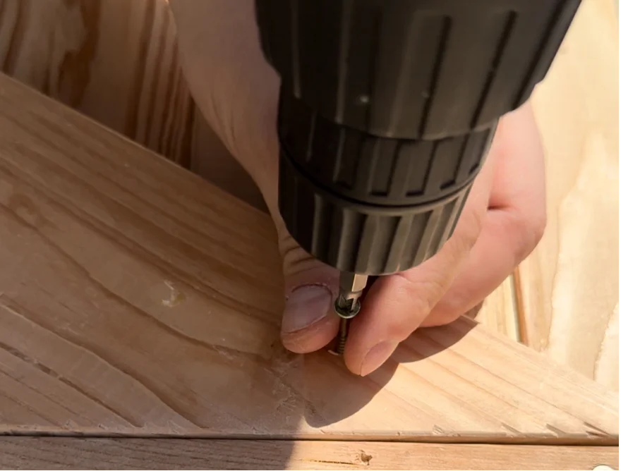 Person verschraubt Holzbalken mit Akkuschrauber
