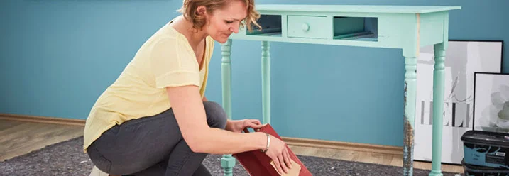 Person schleift Holzkiste mit Schleifpapier ab