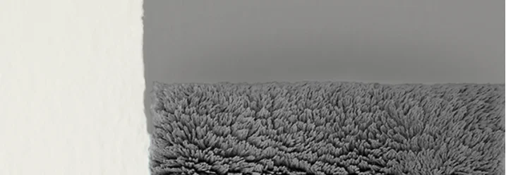 Hand spachtelt graue Farbe an Wand