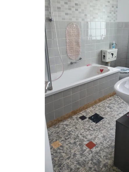 Badewanne mit grauen Fliesen