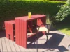 Ein roter selbstgebauter Gartentisch mit zwei Barhockern.