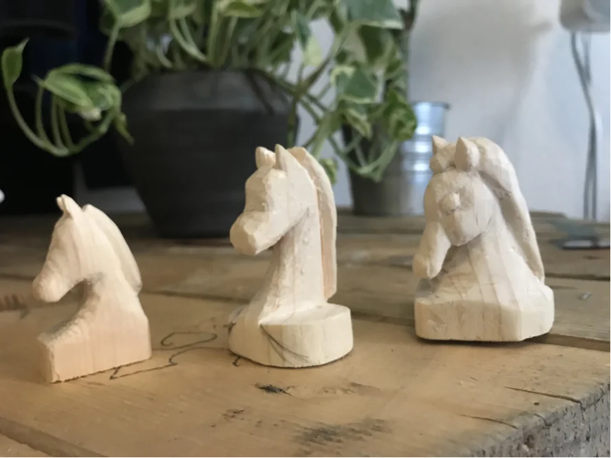 Drei unterschiedlich weit geschnitzte Schachpferde aus Holz