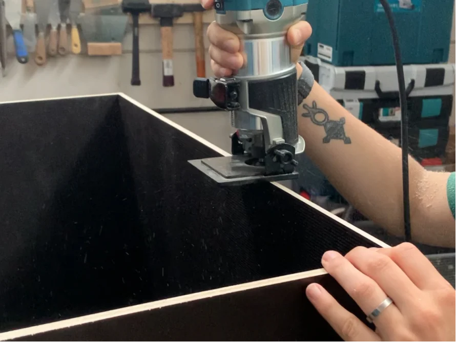 Person fräst Holzplatte mit Oberfräse