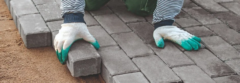Person verlegt Pflastersteine
