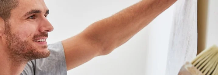 Person bringt Tapete an Wand an