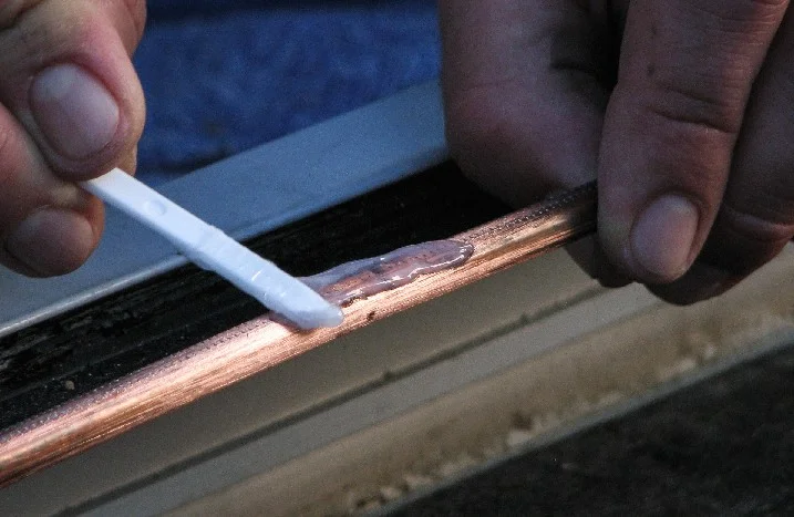 Person trägt Kleber mit Spatel auf