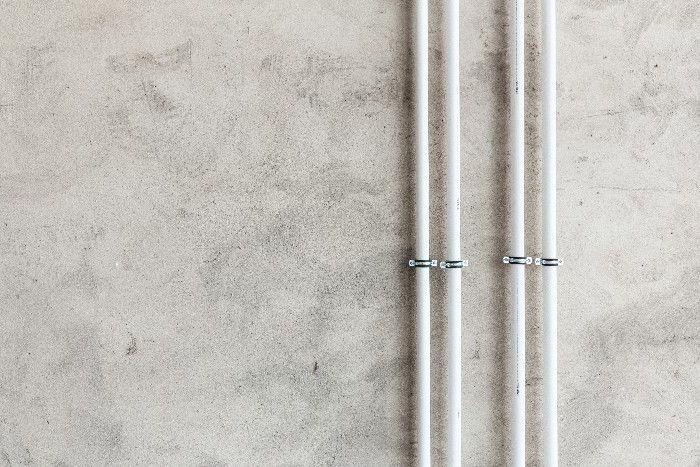 Vier kleine Rohre über einer grauen Wand