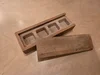 Eine kleine, offene Holzschachtel mit vier Fächern und daneben liegendem Deckel.