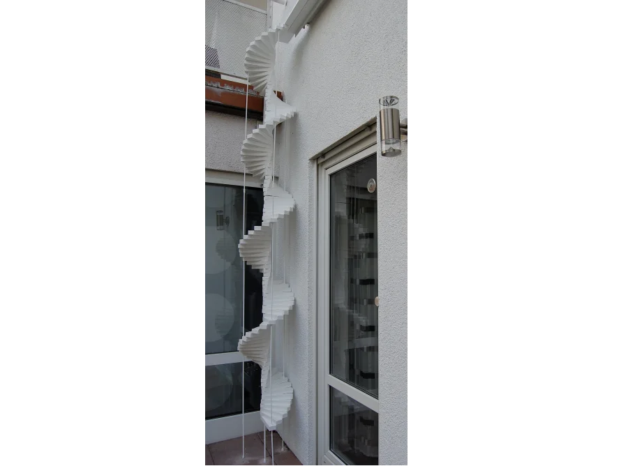 Eine weiße Wendeltreppe an einer Hauswand.
