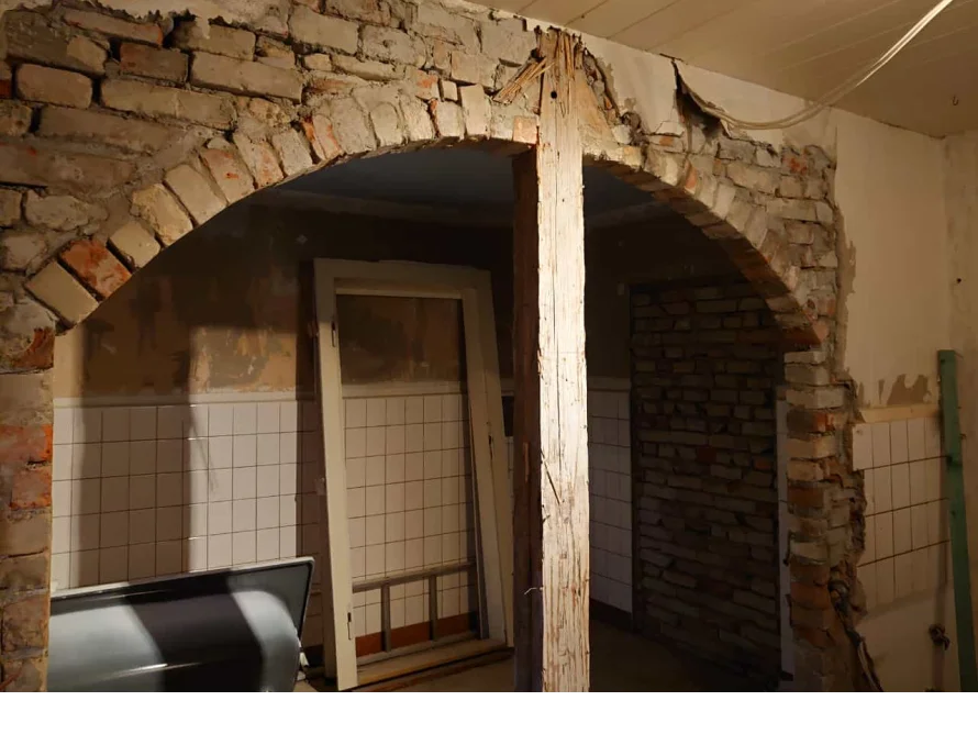 Ein gemauerter Torbogen in einem Raum mit Fliesen.