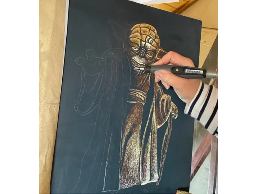 Person graviert eine Zeichnung mit einem Gravierwerkzeug