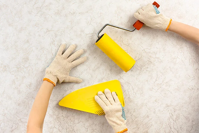 Hände mit Tapezierspachtel und Walze
