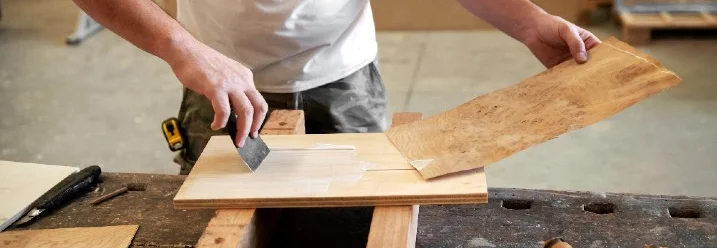 Person trägt Furnier auf Holz auf