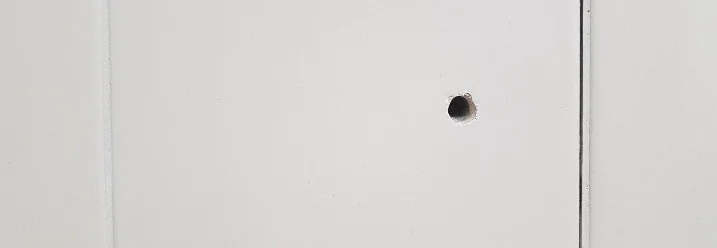 Weiß gekachelte Wand mit Loch