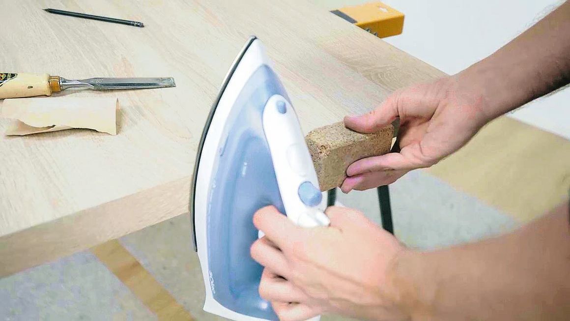 Mit einem Bügleisen wird der Umleimer an den Kanten einer Arbeitsplatte angebracht.