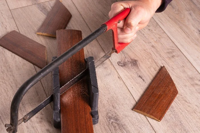 Person sägt Holzbrett mit Bügelsäge