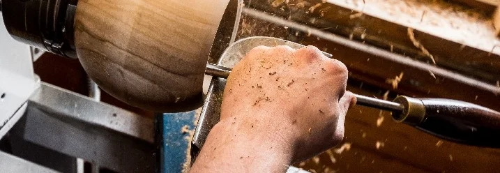 Hand führt Werkzeug an drehendem Holz