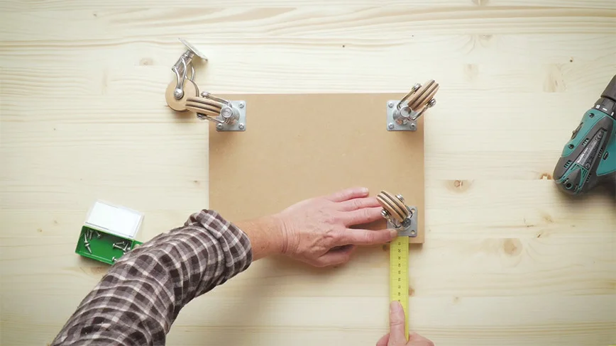 Person misst Holzbrett mit Zollstock aus