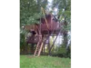 Ein Baumhaus aus Holz mit einer Leiter und einer Seilwinde.
