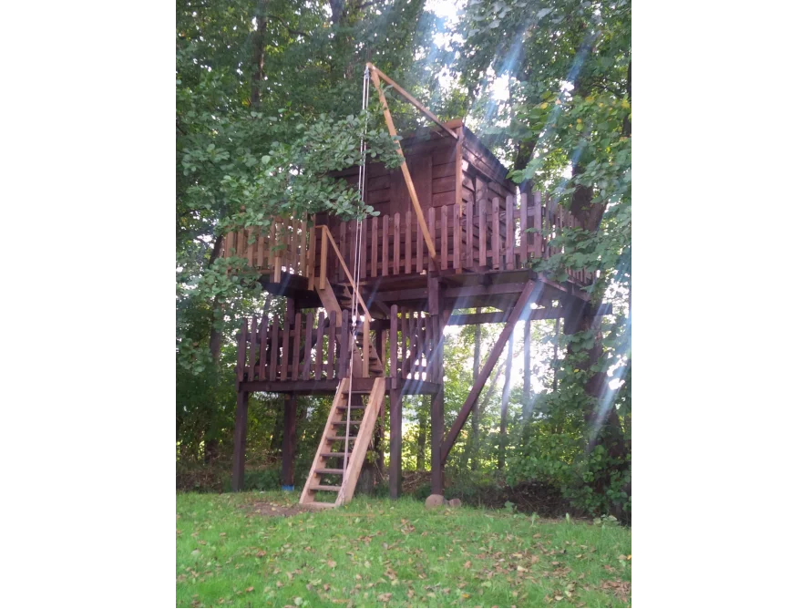 Ein Baumhaus aus Holz mit einer Leiter und einer Seilwinde.