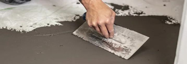 Person verteilt Estrich mit Kelle.