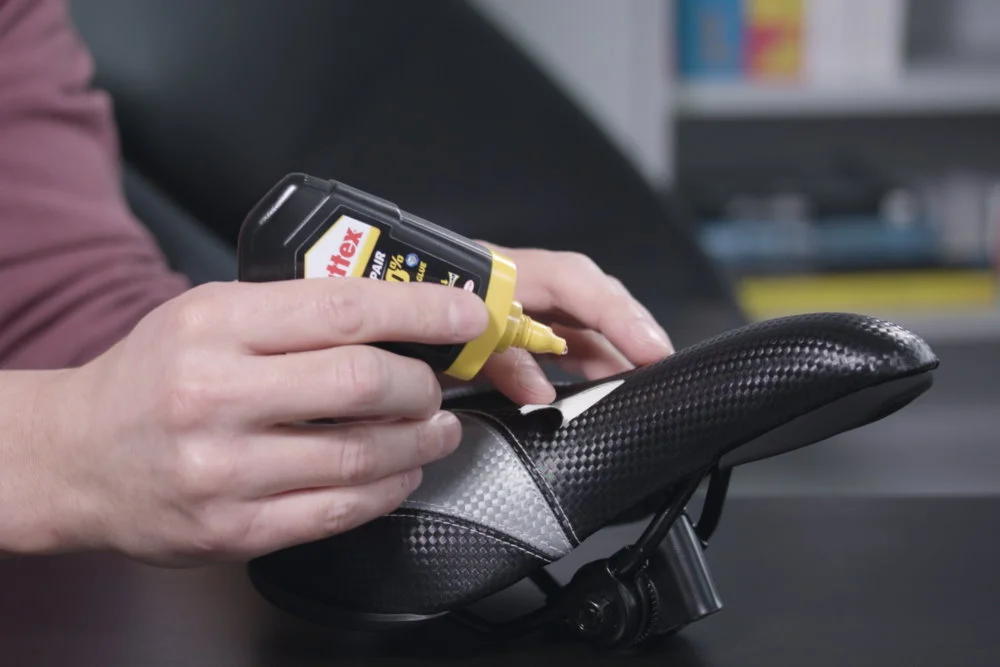 Person klebt einen Fahrradsattel.