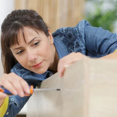 Person schraubt Holzbrett fest