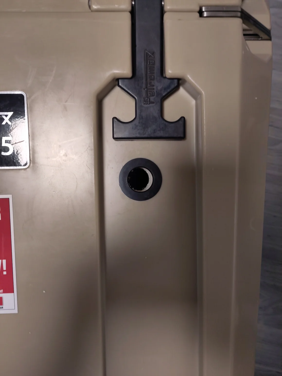 Nahaufnahme des schwarzen Gummi-Verschlusses einer beigefarbenen Kühlbox.