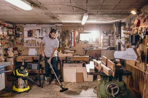 Person saugt Sägespäne in Werkstatt