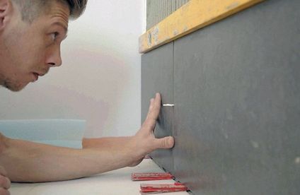 Fliesen verlegen an der Wand Handwerker setzt Fliesenkreuze zwischen Wandfliesen.