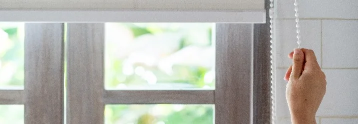 Hand bedient ein Rollo.