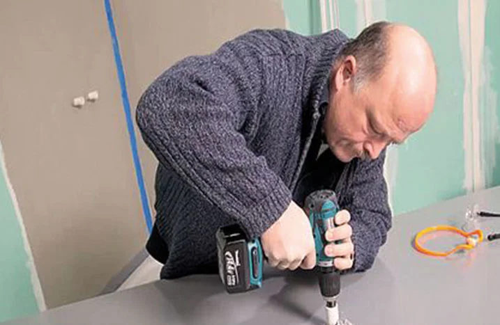 Person bohrt mit Akkuschrauber in Oberfläche