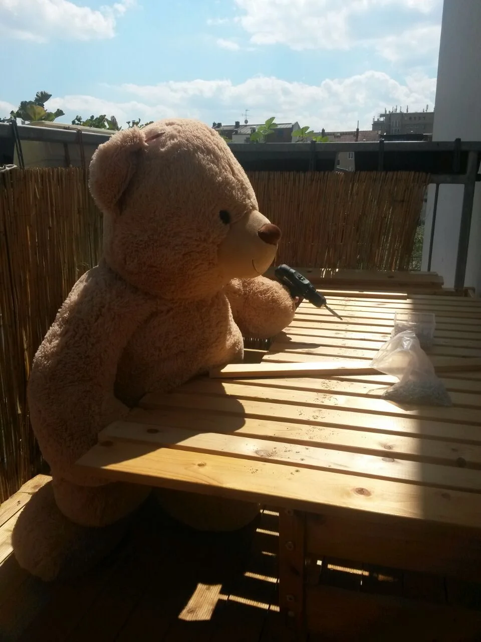 Teddybär baut mit Akkuschrauber ein Holzgestell