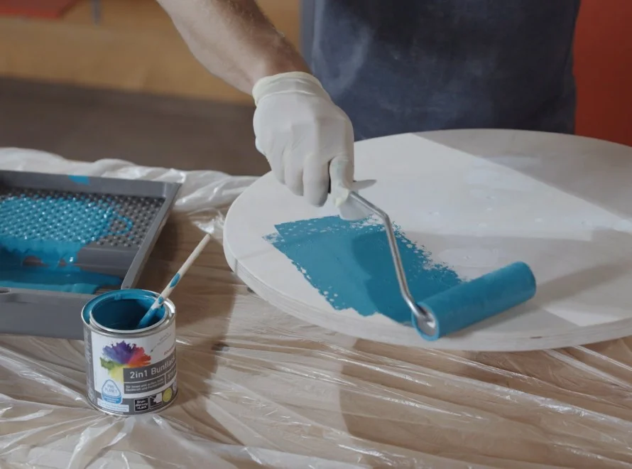 Person streicht Kreisplatte mit Farbe blau