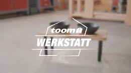 toom Werkstatt Logo mit unscharfem Tisch im Hintergrund