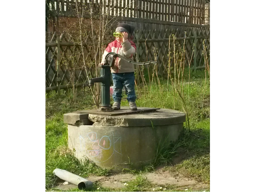 Kleinkind steht auf einem Brunnen