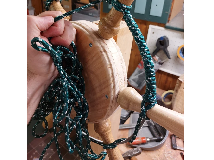 Person bindet ein grünes Seil an ein Holzgestell