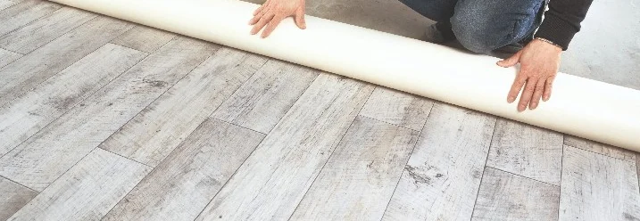 Person rollt einen Vinylboden aus