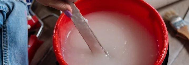 Person rührt Kleister in einem Eimer