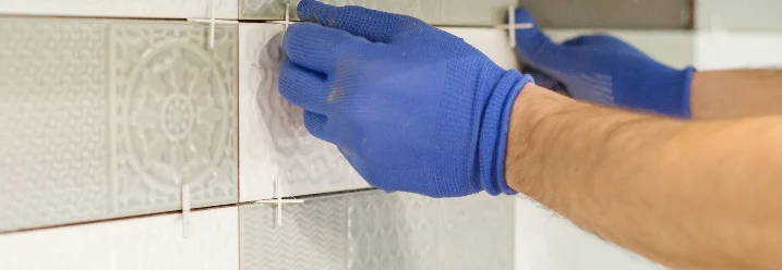 Person bringt Fliesen an Wand an