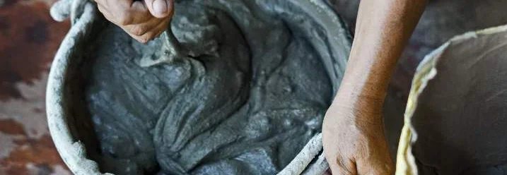 Person mischt Zement in Eimer